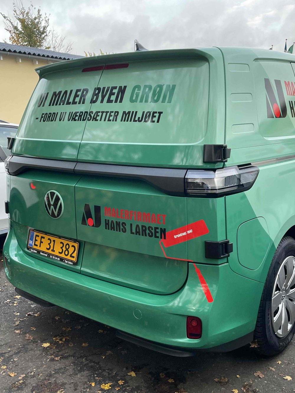 Grøn elvarebil med teksten „Vi maler byen grøn — fordi vi værdsætter miljøet”